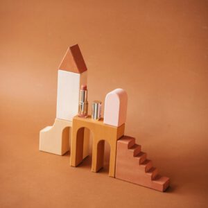 Creative still life with lipsticks on geometric wooden blocks, ideal for beauty campaigns.